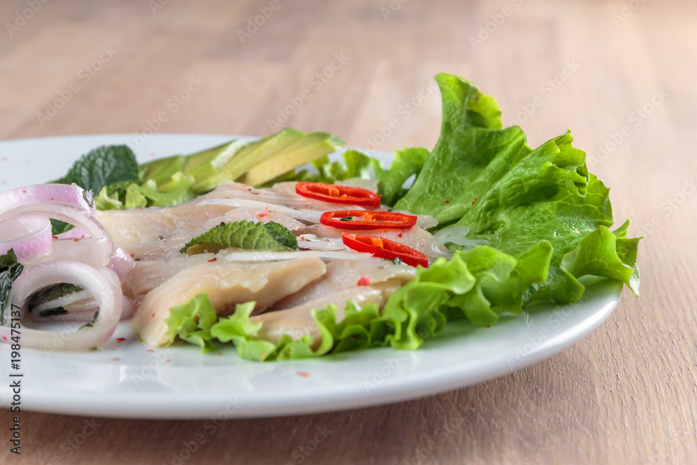 herring fillet with onion, chili pepper and avocado is laid out on a leaf of green salad herring fillet with onion, chili pepper and avocado is laid out on a leaf of green salad