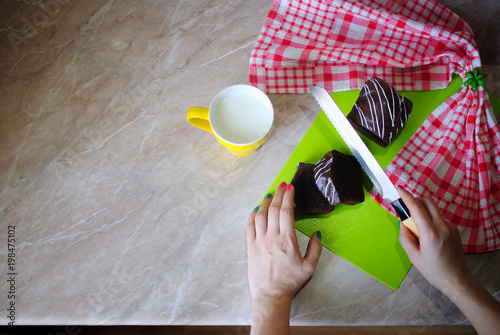Вкусный завтрак с шоколадным кексом. Кекс с молоком на мраморном столе. Нарезаем кекс ножом на кухонной доске.
