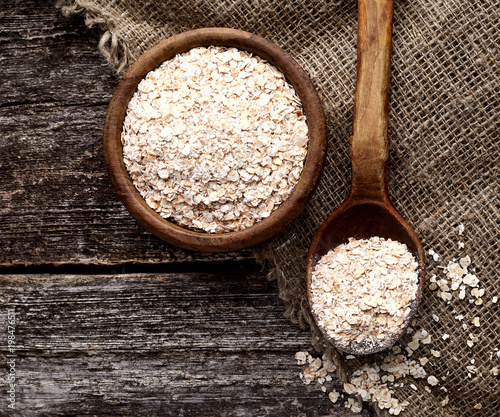 Oatmeal or oat flakes on dark wooden table