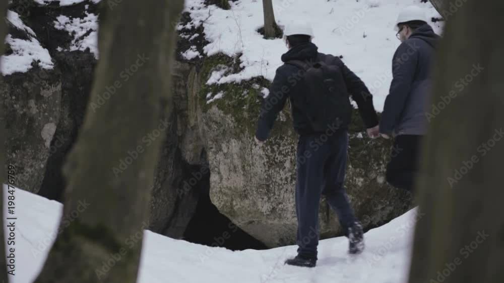 Two speleologists come to enter of the cave in forest Two speleologists come to enter of the cave in forest