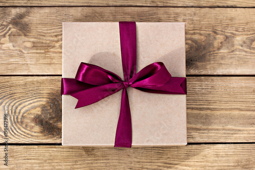Gift. Craft box with a bow on wooden boards.