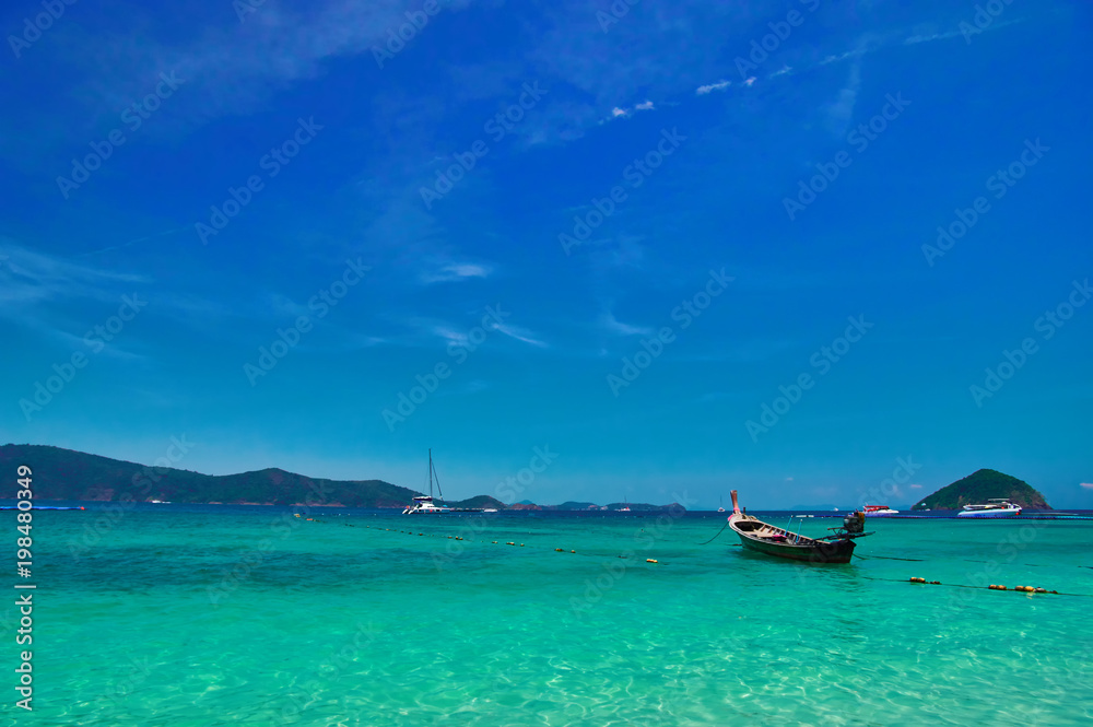 Sea bay with turquoise water and fishing boats under bright sky. Landscape blue clear sky, shimmering sea, background, copy space.