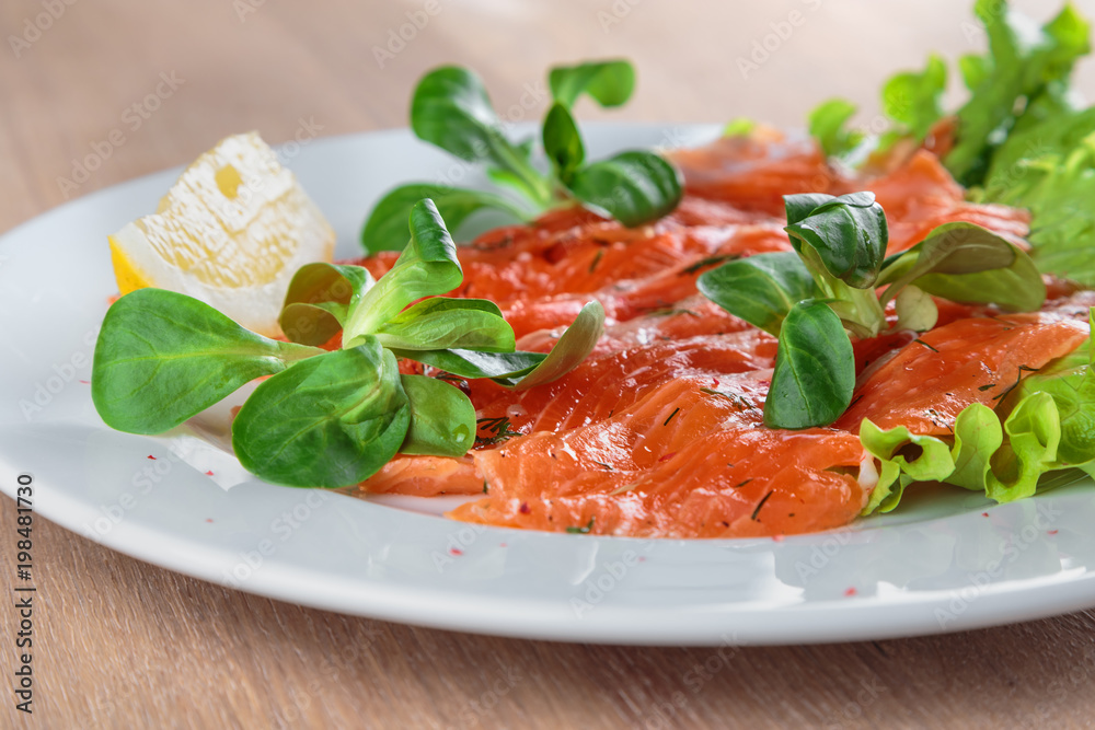 salted salmon with a slice of lemon on a sheet of green salad salted salmon with a slice of lemon on a sheet of green salad