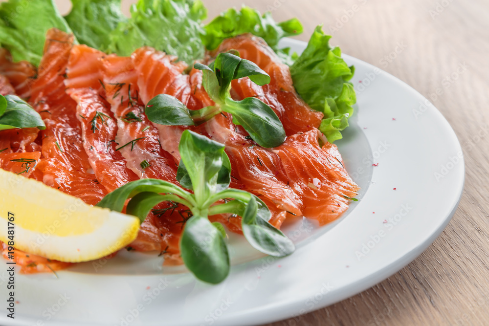 salted salmon with a slice of lemon on a sheet of green salad salted salmon with a slice of lemon on a sheet of green salad