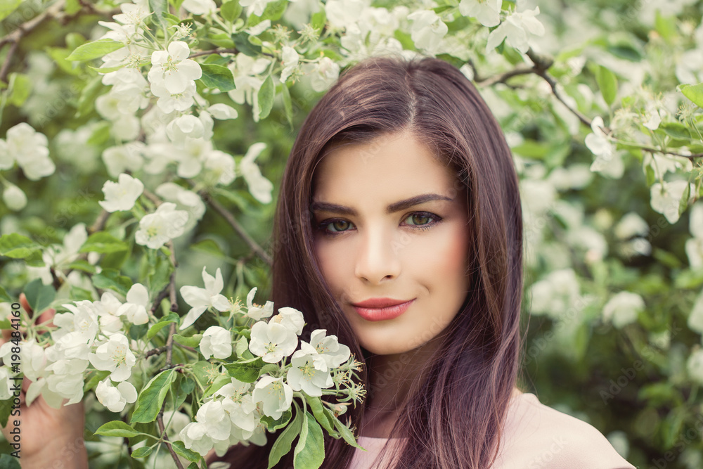 Beautiful female face closeup portrait. Pretty woman in blossom spring flowers background Beautiful female face closeup portrait. Pretty woman in blossom spring flowers background