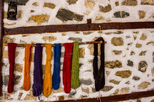 Coloured woollen yam / yarn / tread hanging on stone and wood wall in the yard of Bulgarian traditional house from 18th century, Zlatograd, Bulgaria photo