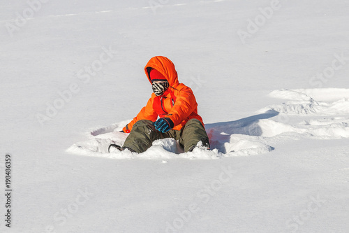 young boy stands in white snow clearing