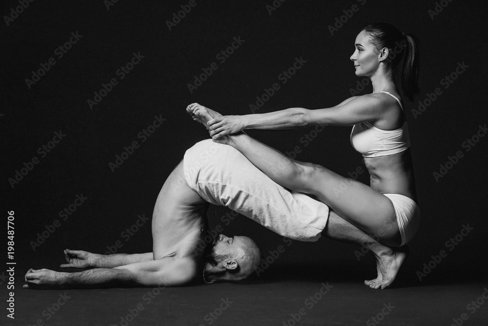 Monochrome portrait of beautiful sporty couple: woman and man in white clothes doing yoga asanas together indoor Monochrome portrait of beautiful sporty couple: woman and man in white clothes doing yoga asanas together indoor