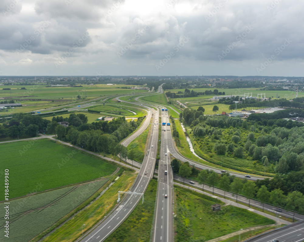 Highway in Holland, Netherlands with canal viewed from plane in sky with clouds