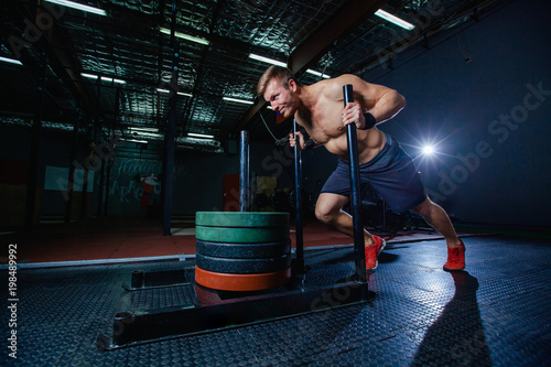 sled push man pushing weights workout exercise at gym. Cross fit style