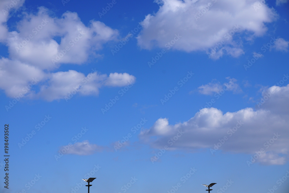 Two street lights in daylight against a beautiful blue sky with white clouds Two street lights in daylight against a beautiful blue sky with white clouds