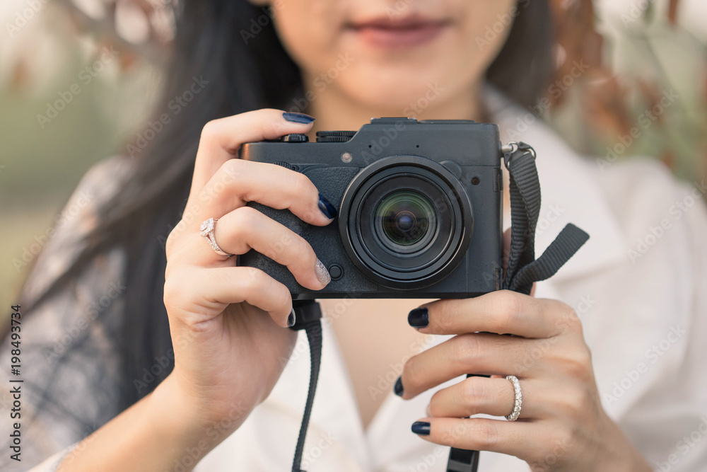 Young woman taking photos with camera on the field. Cute woman with her camera in hands, with sunlight in the morning. Young woman taking photos with camera on the field. Cute woman with her camera in hands, with sunlight in the morning.