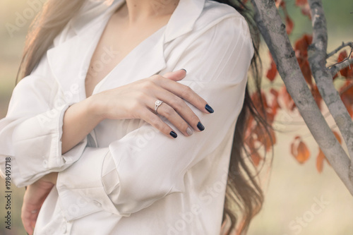 An elegant engagement diamond ring on woman finger. love and wedding concept. Diamond ring on woman's finger before wedding with outdoor background.