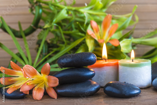 Spa concept with massage stones  orange flowers  green bamboo stems and burning candles