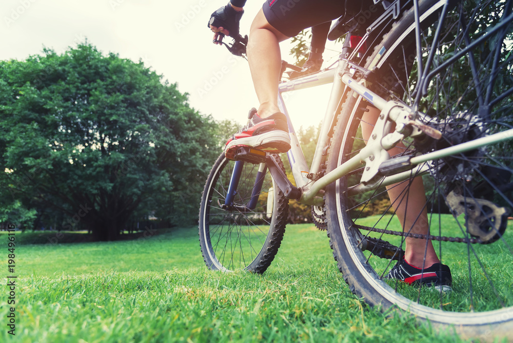 Obraz premium Cycling in park concept. Closeup of bicycle on green field at park in sunset. Picture for add text message. Backdrop for design art work.