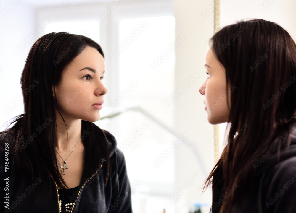 young beautiful girl looks at herself in mirror young beautiful girl looks at herself in mirror