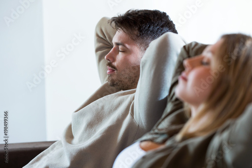 Beautiful young relaxed couple sleeping on the sofa at home.