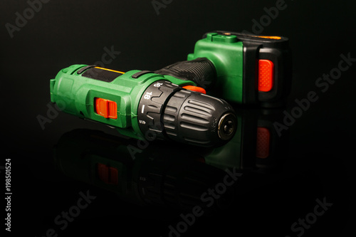 Cordless screwdriver, cordless drill isolated on a black background with reflection.