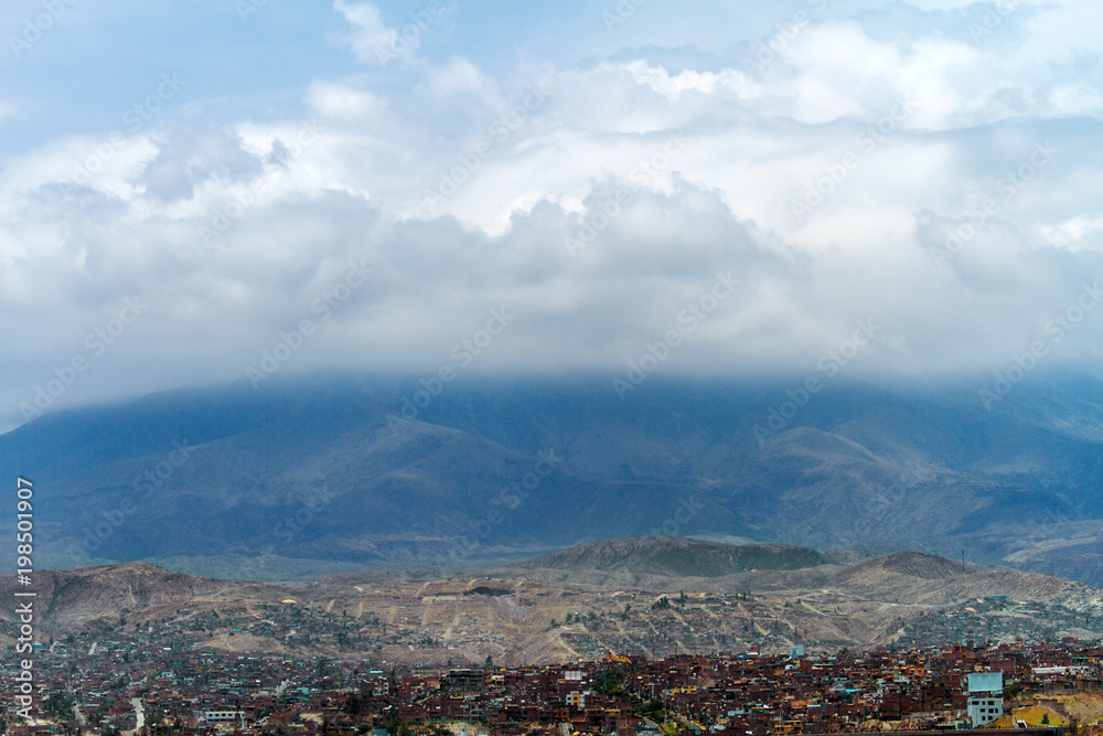 Misti volcano covered by clouds with Arequipa neighborhood (Peru) at its base