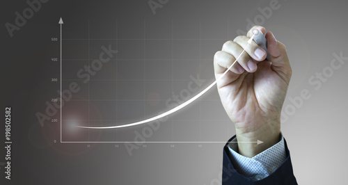 Close up of a businessman’s hand drawing an exponential line curve showing of business growth and success rapidly. photo