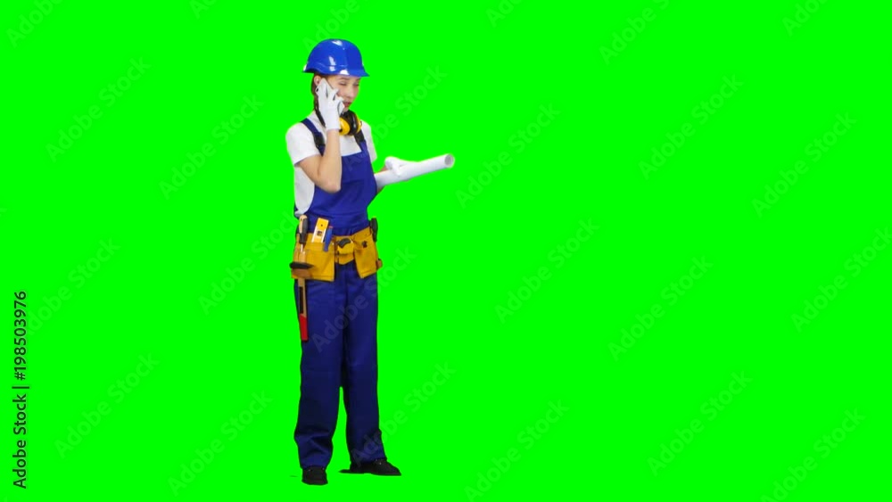 Engineer is standing and talking on the phone with a drawing in her hands. Green screen Engineer is standing and talking on the phone with a drawing in her hands. Green screen