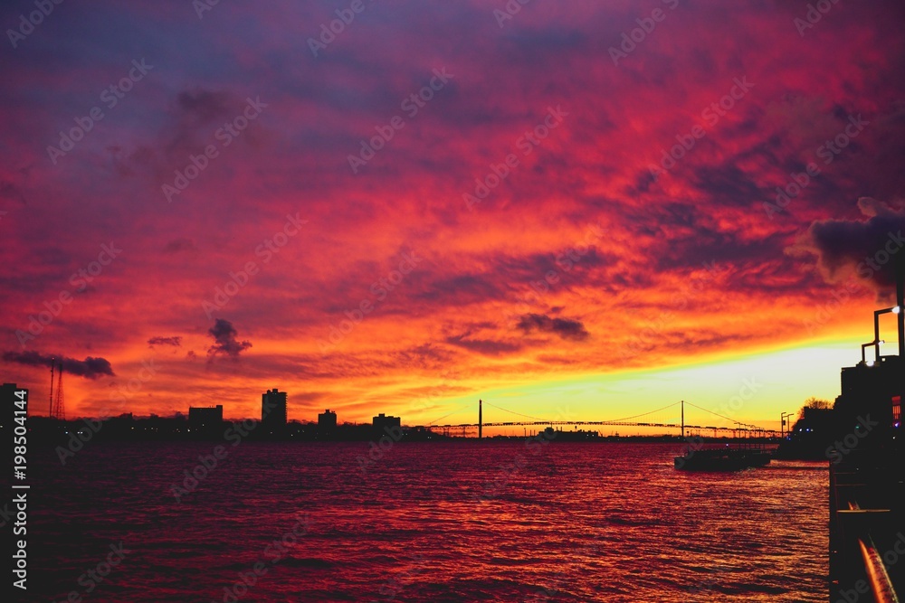 orange and pink sunset on the Detroit river looking at the Ambassador Bridge