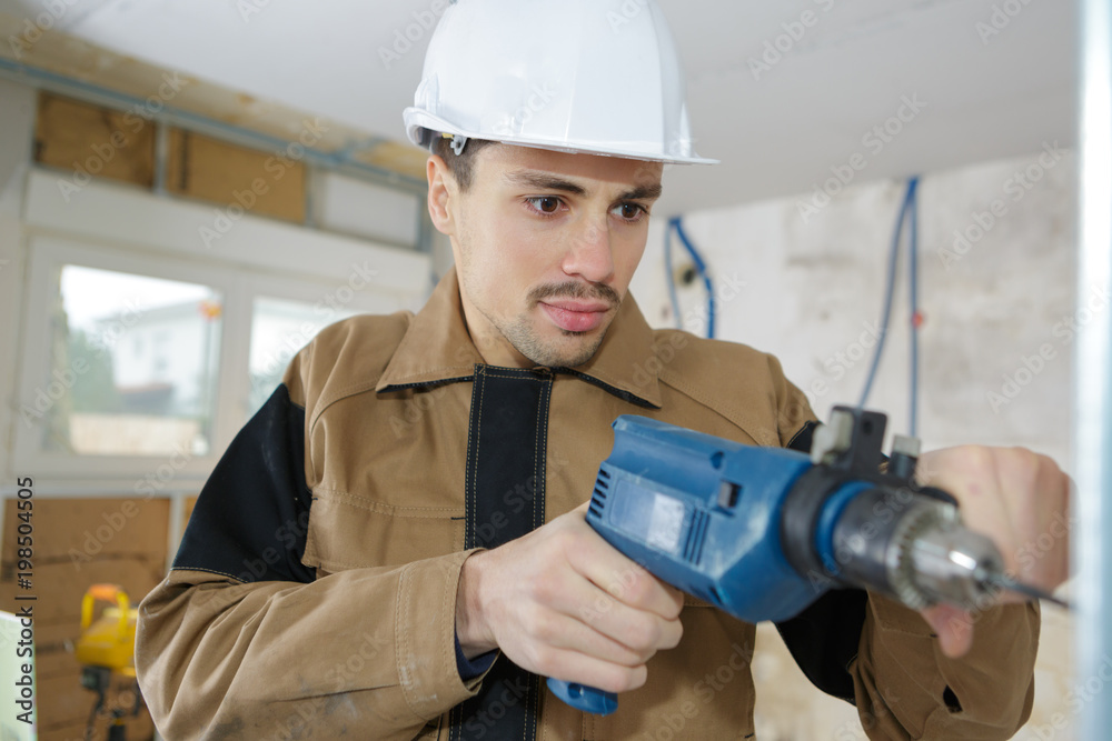 young man drilling hole in wall young man drilling hole in wall