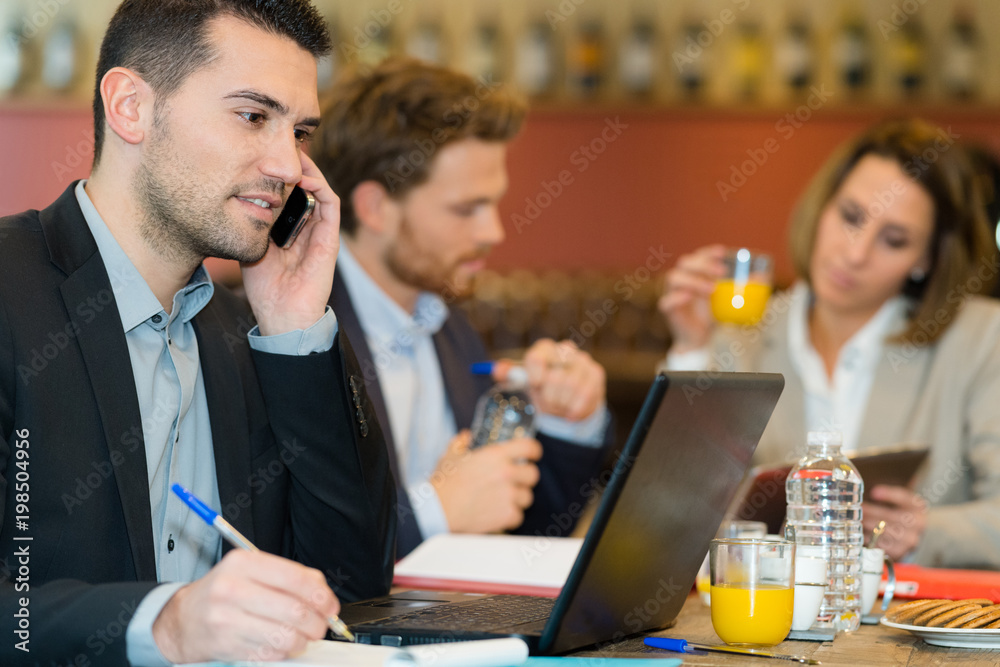 attractive businessman using mobile phone while having lunch