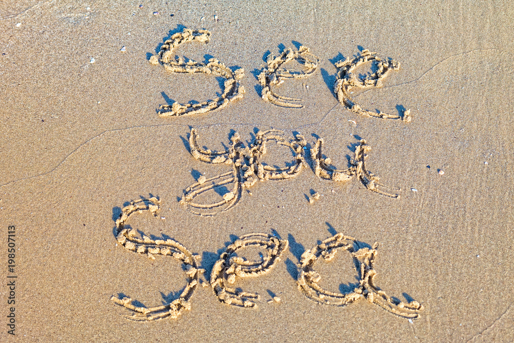 See you Sea on the beach written in the sand.