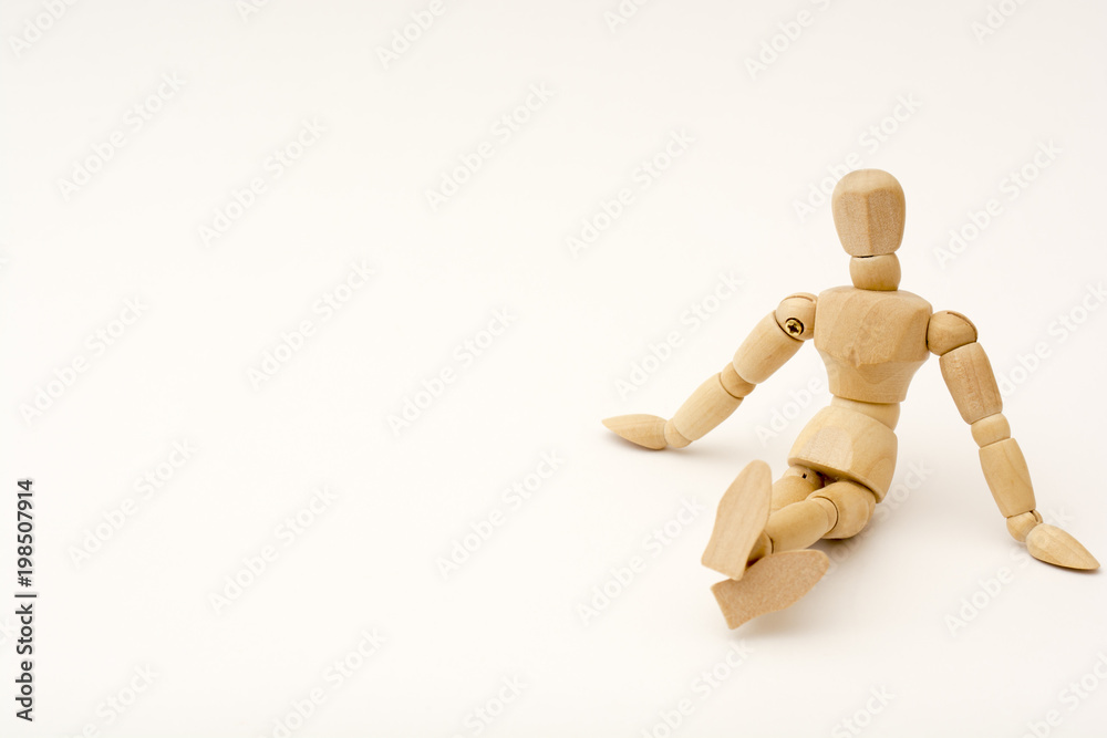A wooden person sits on the floor, his legs are crossed, head looks at the viewer A wooden person sits on the floor, his legs are crossed, head looks at the viewer