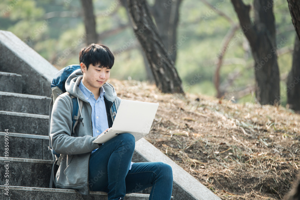 Asian man backpacking using laptop Asian man backpacking using laptop