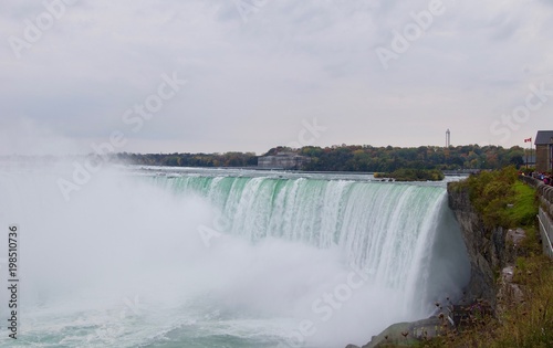 Beautiful and impressive panorama of the Niagara Falls in Ontario  Canada  on a bright colorful  red  orange  yellow  autumn day with water crashing down the falls onto rocks creating lots of mist