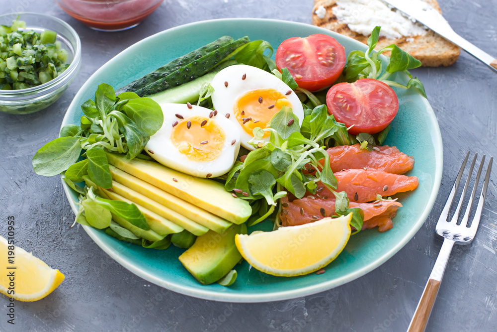 Healthy salad with avocado, corn salad, smoky salmon, eggs and tomatoes for breakfast. Close up