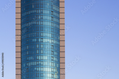 A multi-storey brick building under construction  against a blue sky background. High multi-story building. Skyscraper. Blue windows. Mirror