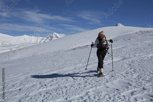 Mujer joven con raquetas de nieve paseando en alta montaña