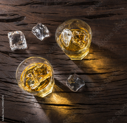 Whiskey glasses or glasses of whiskey with ice cubes on the wooden table. Top view.