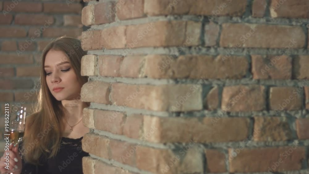 A beautiful girl is in a wine cellar.
Horizontal ( from right to left ) pan.
A serious girl with a glass of champagne is stands near the old brick wall and drink. A beautiful girl is in a wine cellar.
Horizontal ( from right to left ) pan.
A serious girl with a glass of champagne is stands near the old brick wall and drink.