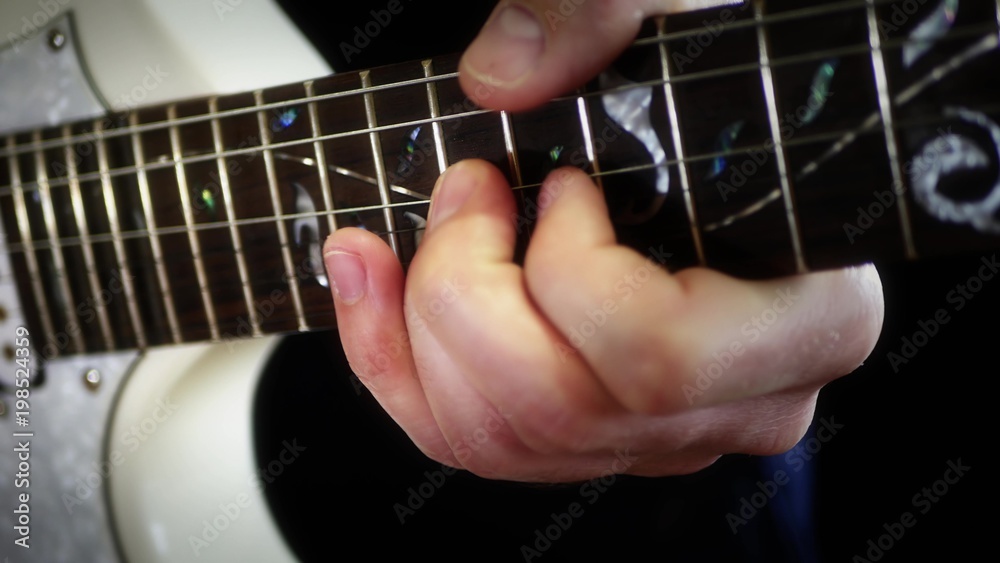 A musician plays solo on a white electric guitar on a black background, close-up - 2. The man is playing rock. A musician plays solo on a white electric guitar on a black background, close-up - 2. The man is playing rock.