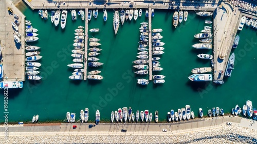 Aerial bird's eye view of Latchi port, Akamas peninsula, Polis Chrysochous, Paphos, Cyprus. The Latsi harbour with boats and yachts aligned, fish restaurants, promenade, beach tourist area from above. photo