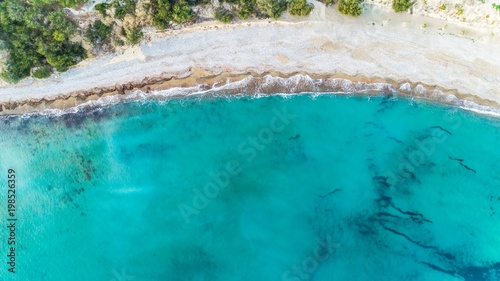 Fototapeta Naklejka Na Ścianę i Meble -  Aerial bird's eye view of Pissouri bay, a village settlement between Limassol and Paphos in Cyprus. The shore, beach with white sand pebbles and crystal clear clean blue water on the shore from above.