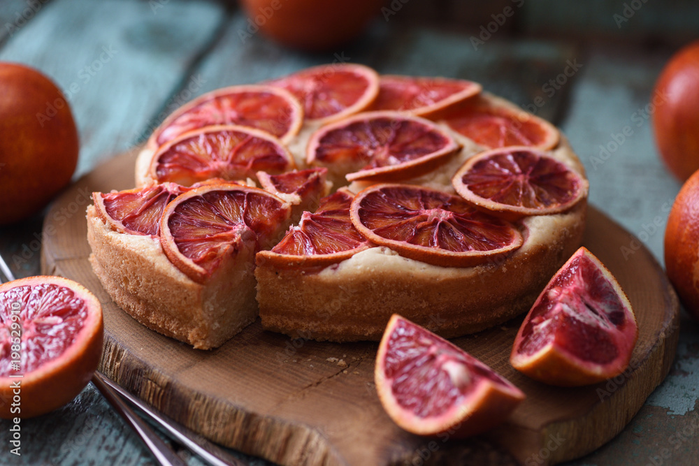 Homemade fruit cake. Blood orange slices on cake served on oak board
