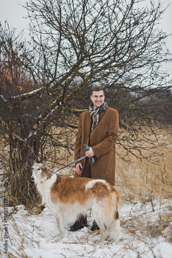 Portrait of a man walking with a dog on the background of the wi