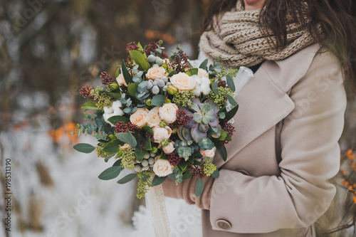 The original bouquet of flowers in the hands of women against the winte