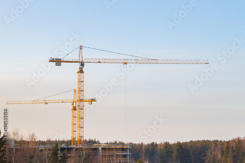 Construction cranes at a construction site at sunset in early spring