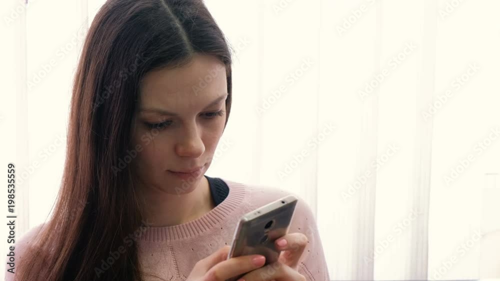 Young woman brunette is typing a message on her mobile phone and looking at screen. Young woman brunette is typing a message on her mobile phone and looking at screen.