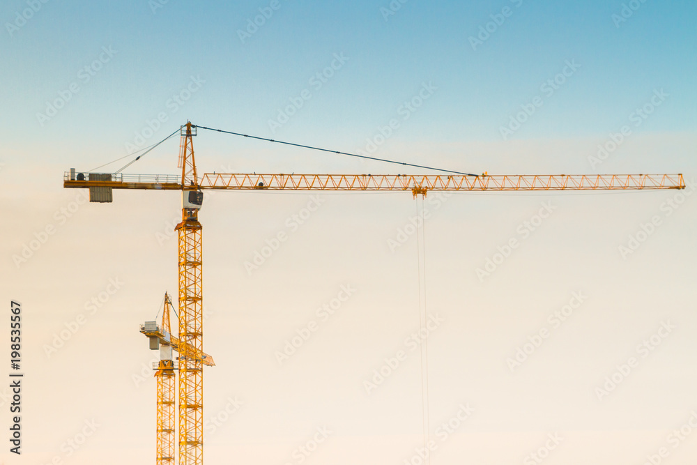 Construction cranes at a construction site at sunset in early spring