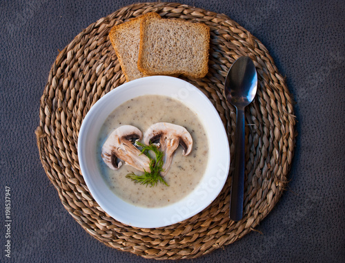 Mushroom creamy soup with small toasts on staw support. Healthy food, vegetarian meal. photo