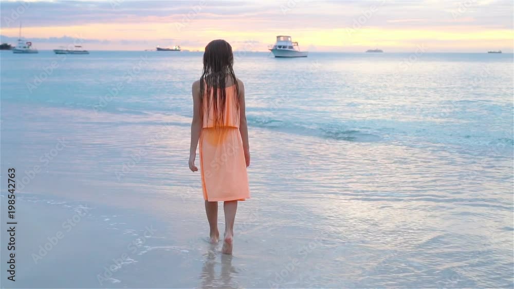 Adorable happy little girl walking on white beach at sunset. SLOW MOTION VIDEO Adorable happy little girl walking on white beach at sunset. SLOW MOTION VIDEO