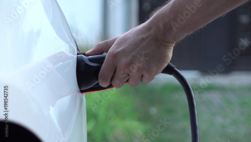 CLOSE UP: Man plugging in Tesla electric car at super charging station