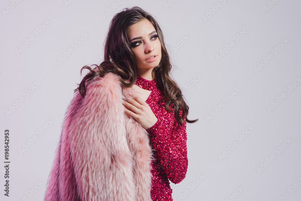 Beautiful Face of Young Woman with Clean Fresh Skin and wavy hair isolated on white and pink background. Girl in red dress and fur coat. Beauty Portrait. Pure Beauty Model Skin Care.